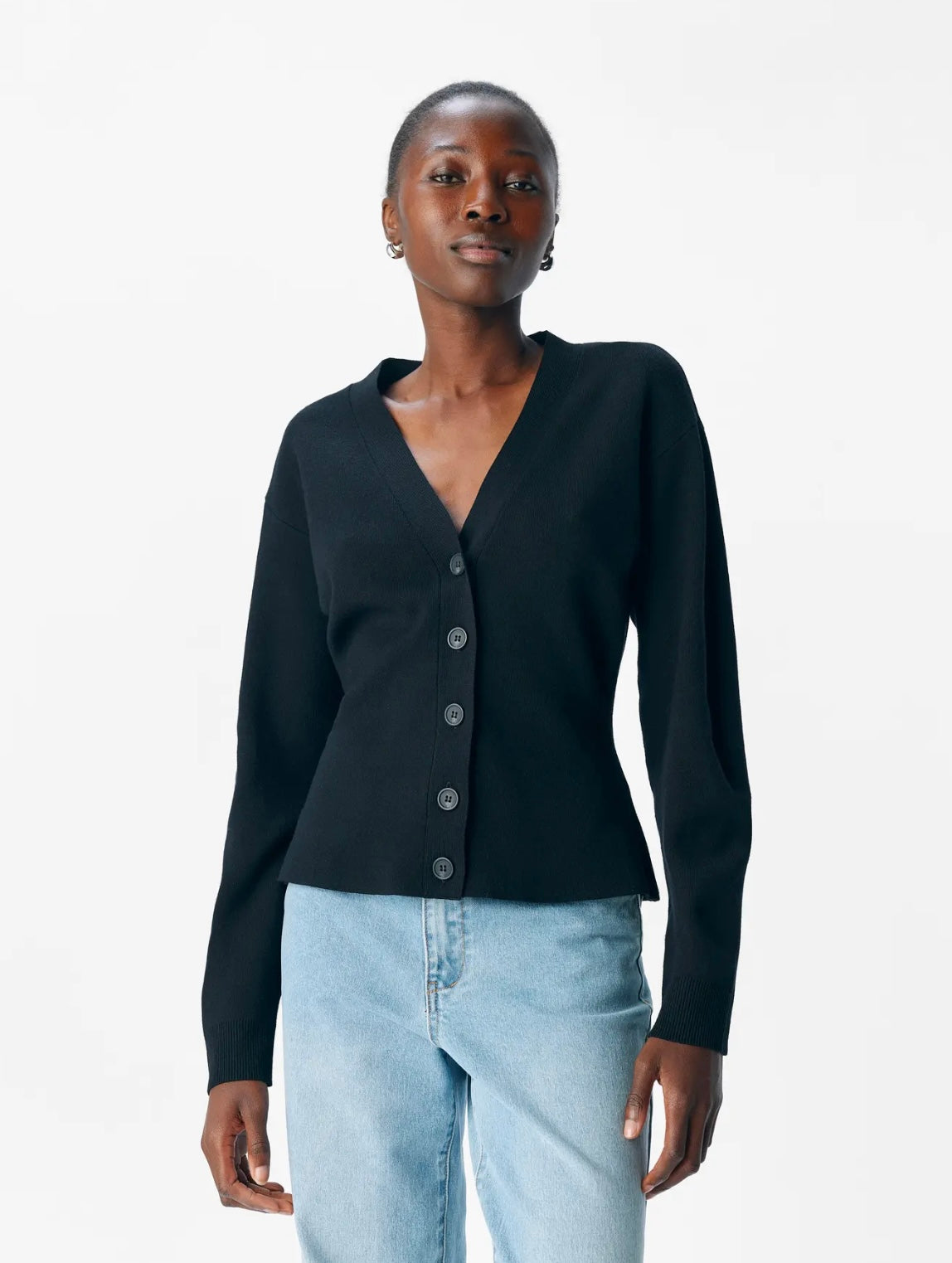 Woman wearing a black cardigan and light blue jeans on a white background