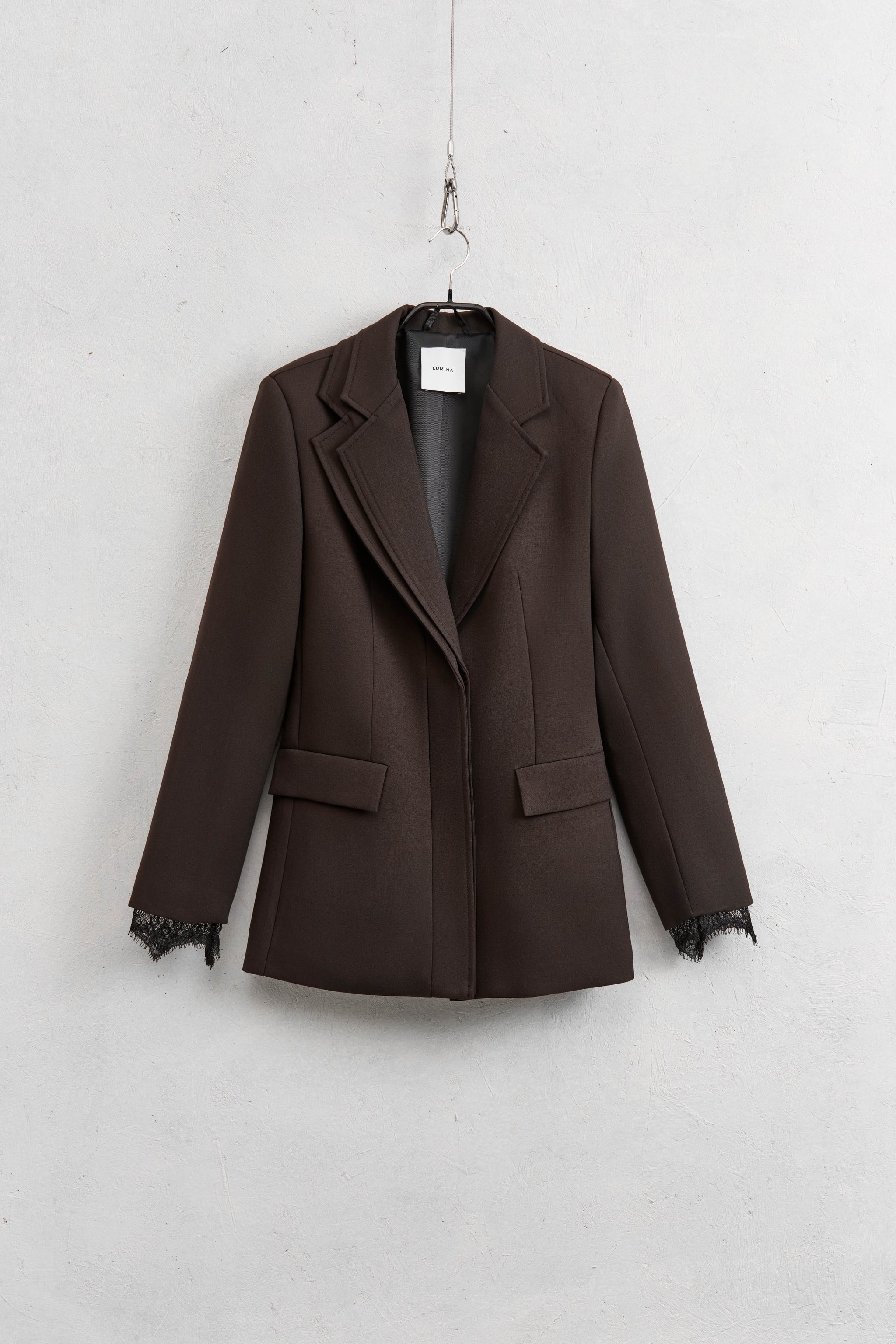 Brown blazer on a hanger against a white background