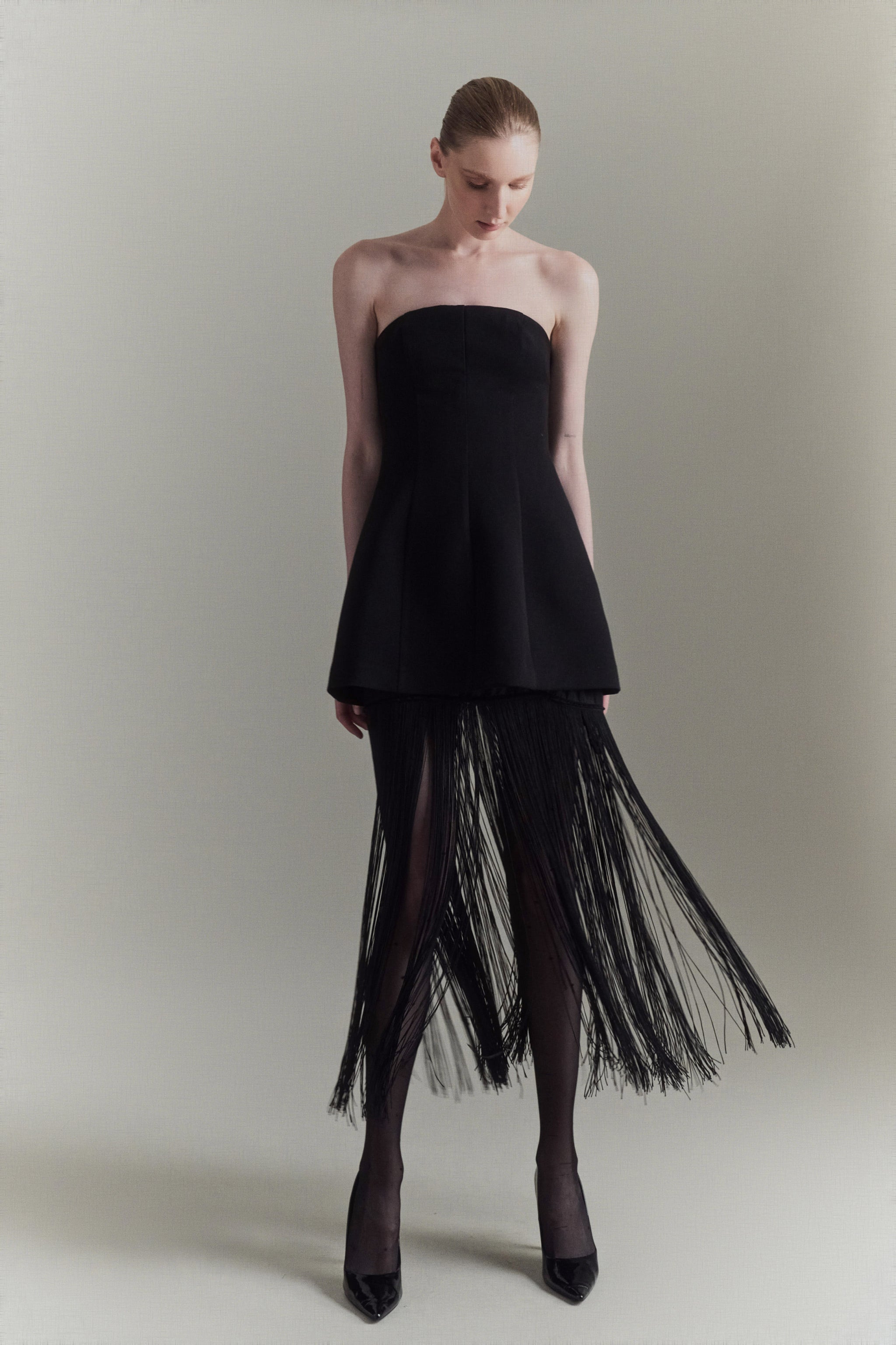 Black strapless dress with fringe detail on a plain background